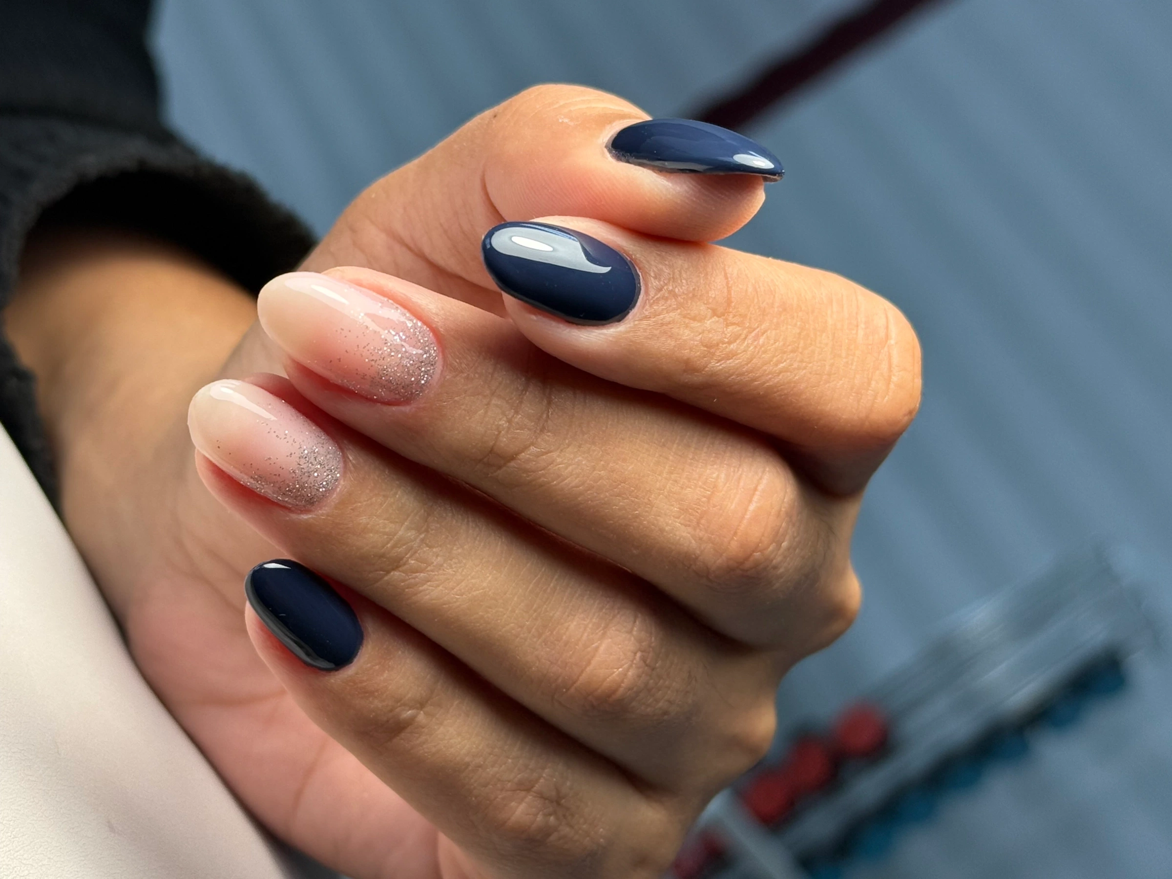 Unhas em azul escuro e rosa claro com acabamento brilhante.