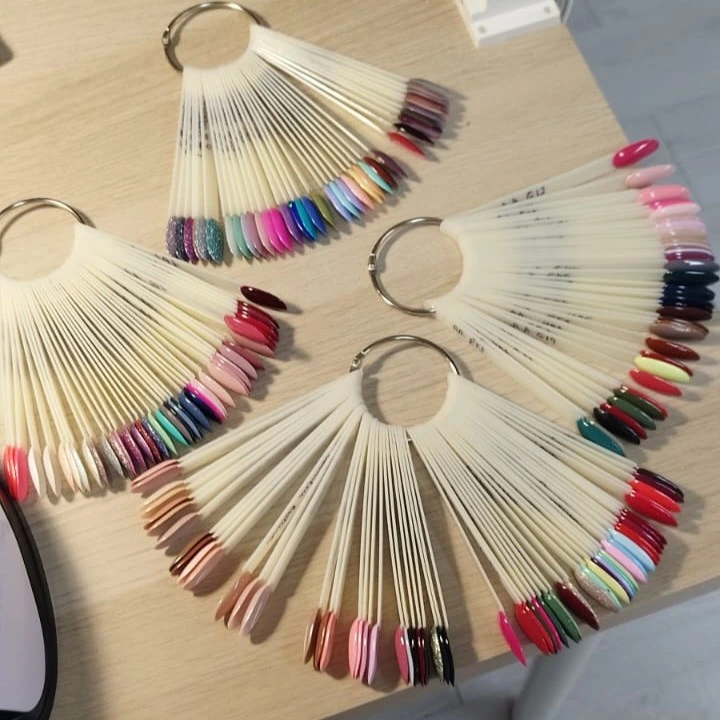 Leques de amostras de vernizes em várias cores sobre uma mesa.